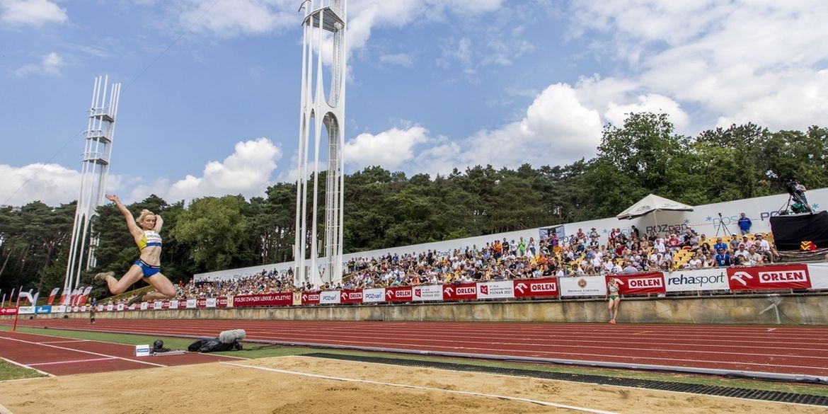 Stadion lekkoatletyczny - kobieta skacze w dal - w tle trybuny pełne kibiców